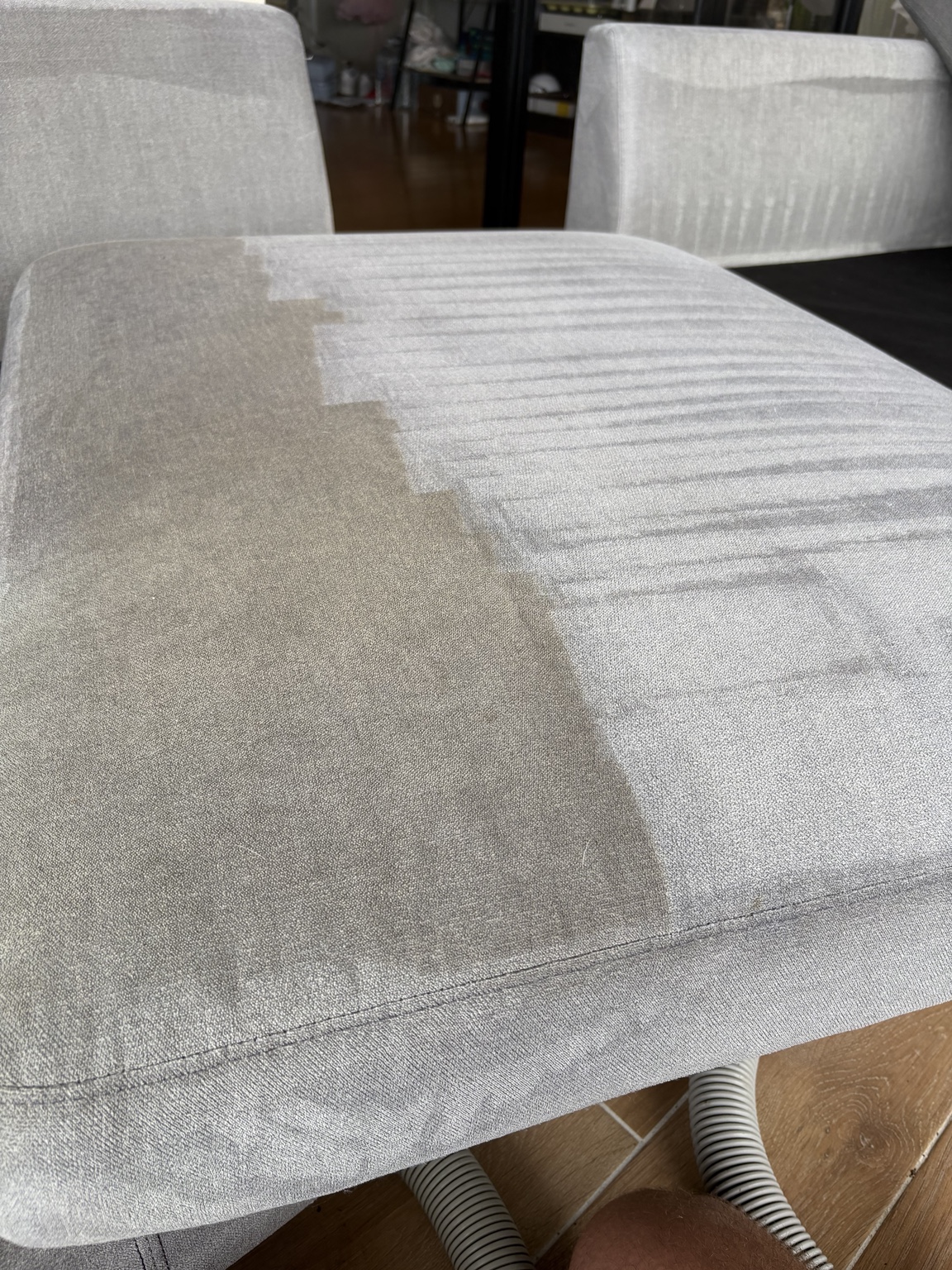 Outdoor sofa cushion during upholstery cleaning in Upper Coomera, showing cleaned and soiled areas